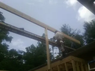 Carpenter setting a ridge beam over a new addition frame — Ice Dam Removal by Roofing Brothers in Eva
