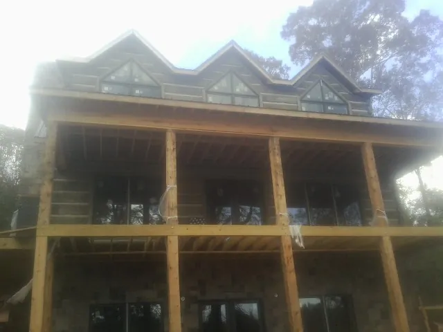 Dormers and porch framing on a large log home under construction — Roof Coating work by our crew in Eva