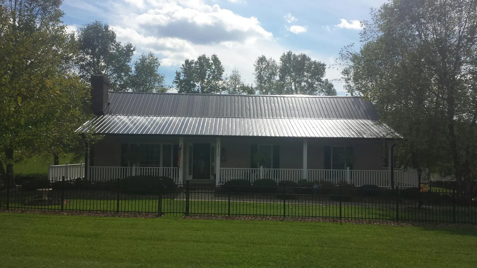 Gray metal roof on a brick ranch with a full width front porch — Gutter Guard Installation work by our crew in Eva
