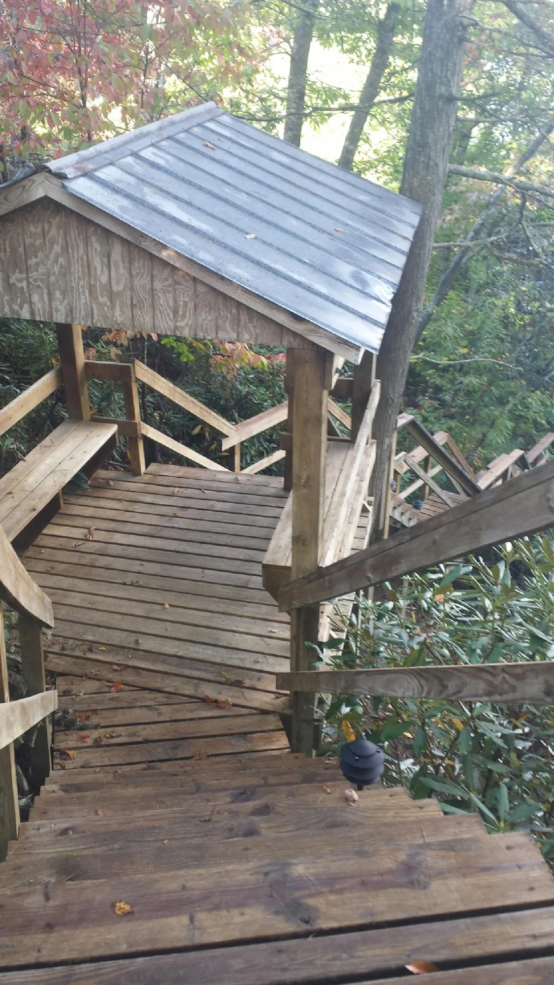 Metal roofed shelter over wooden steps on a wooded walkway — Skylight Repair & Installation work by our crew in Eva